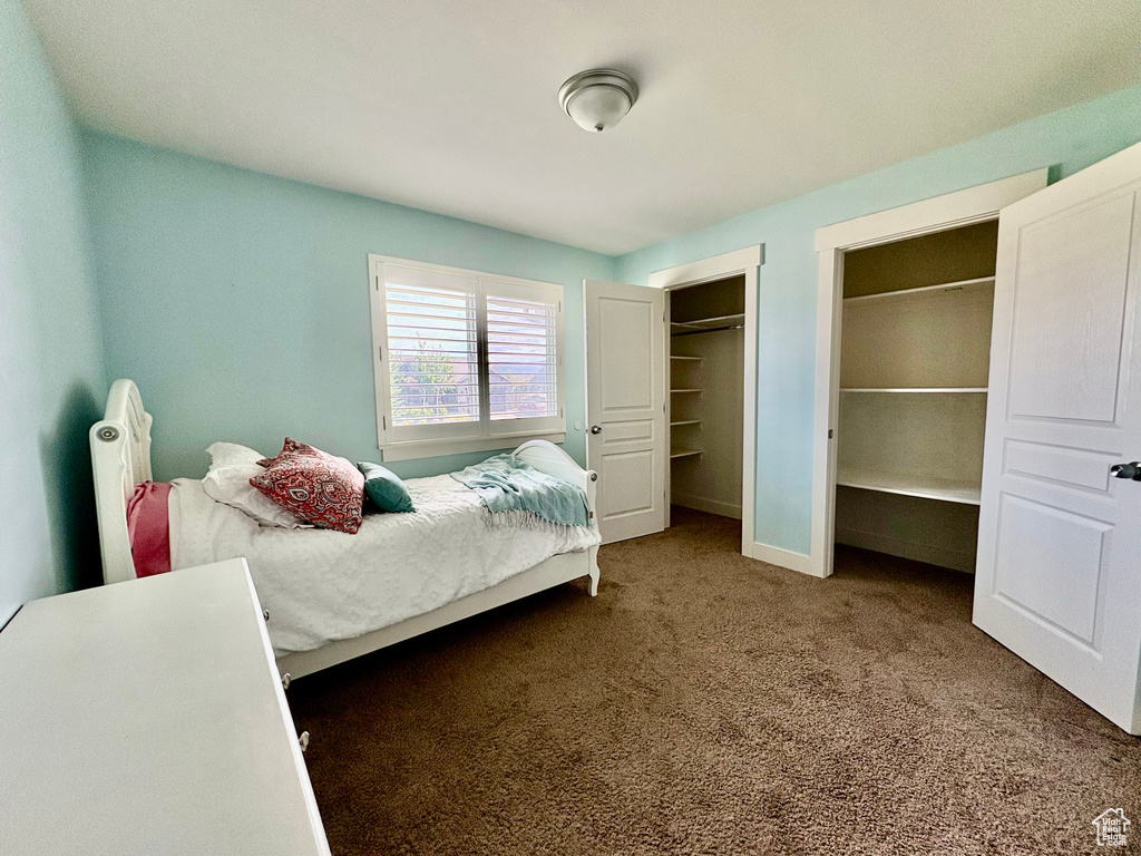 Carpeted bedroom with multiple closets and baseboards