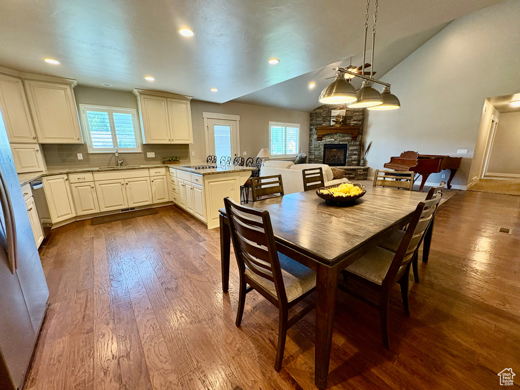 Dining room with a fireplace, lofted ceiling, dark wood-style floors, and recessed lighting