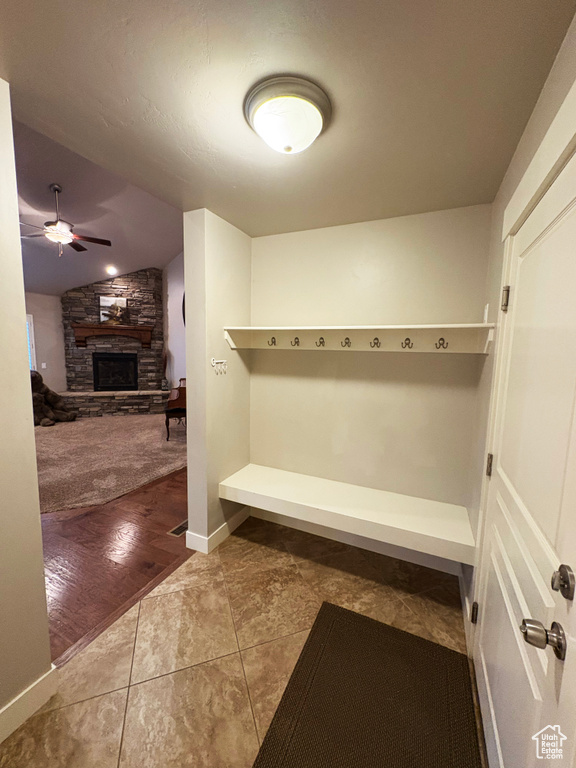 Mudroom featuring a stone fireplace, ceiling fan, vaulted ceiling, and tile patterned floors