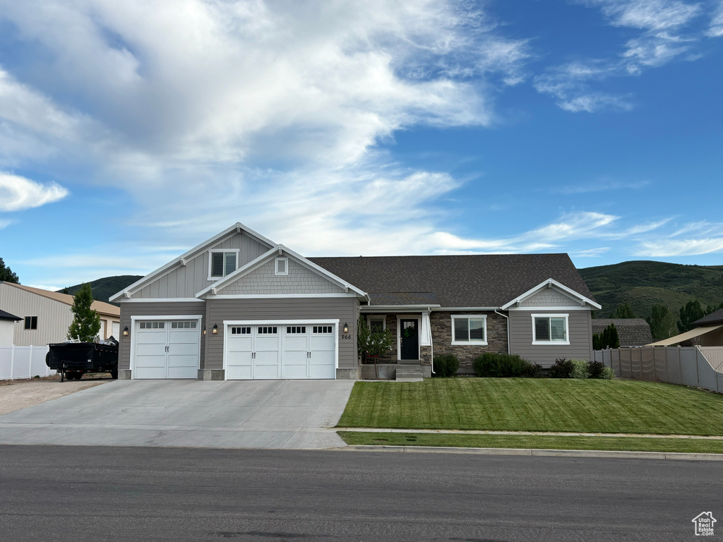 Craftsman house featuring an attached garage, concrete driveway, stone siding, and a mountain view