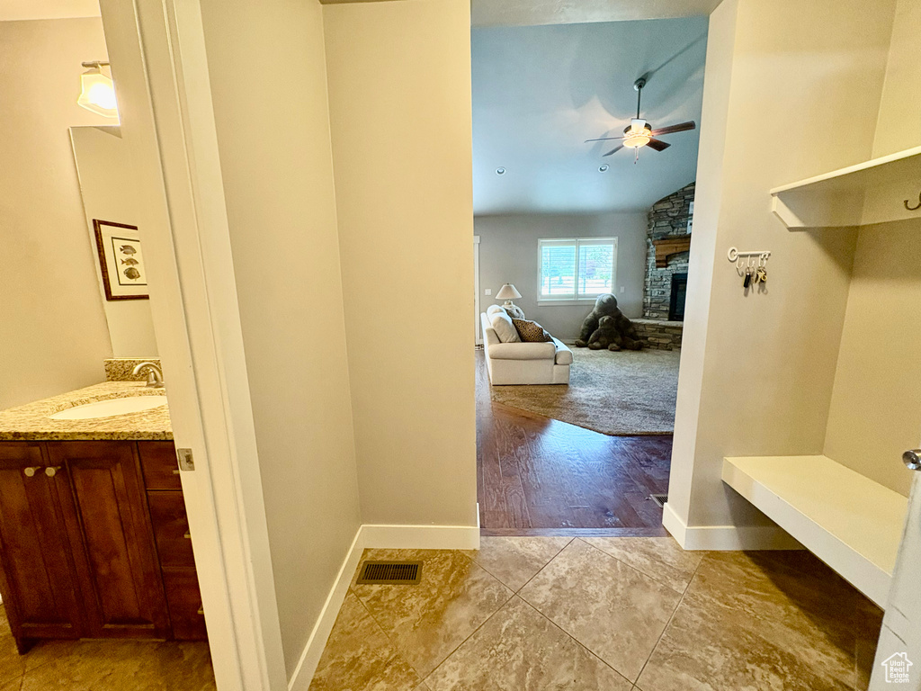 Mudroom featuring a ceiling fan, a fireplace, lofted ceiling, and light tile patterned floors