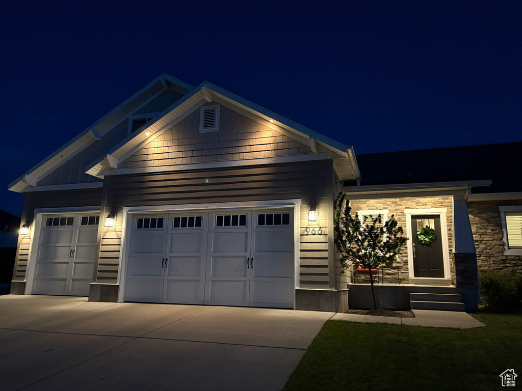 View of front facade featuring a garage, concrete driveway, and stone siding