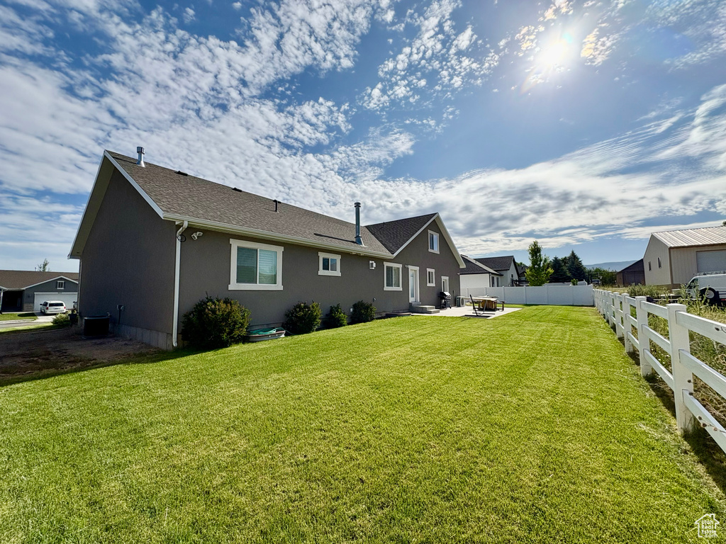 Rear view of house with a patio area, stucco siding, and roof with shingles