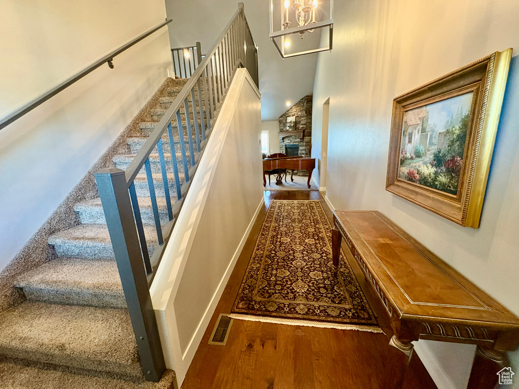 Stairway featuring wood finished floors, a towering ceiling, a fireplace, and a chandelier