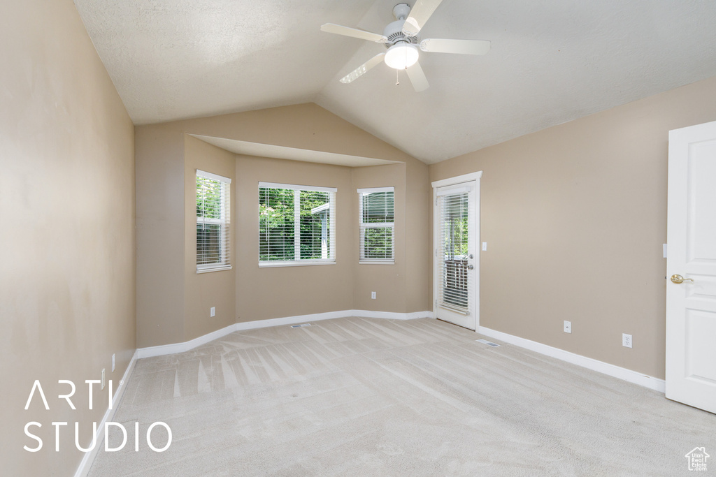 Unfurnished room with a ceiling fan, plenty of natural light, light carpet, and lofted ceiling