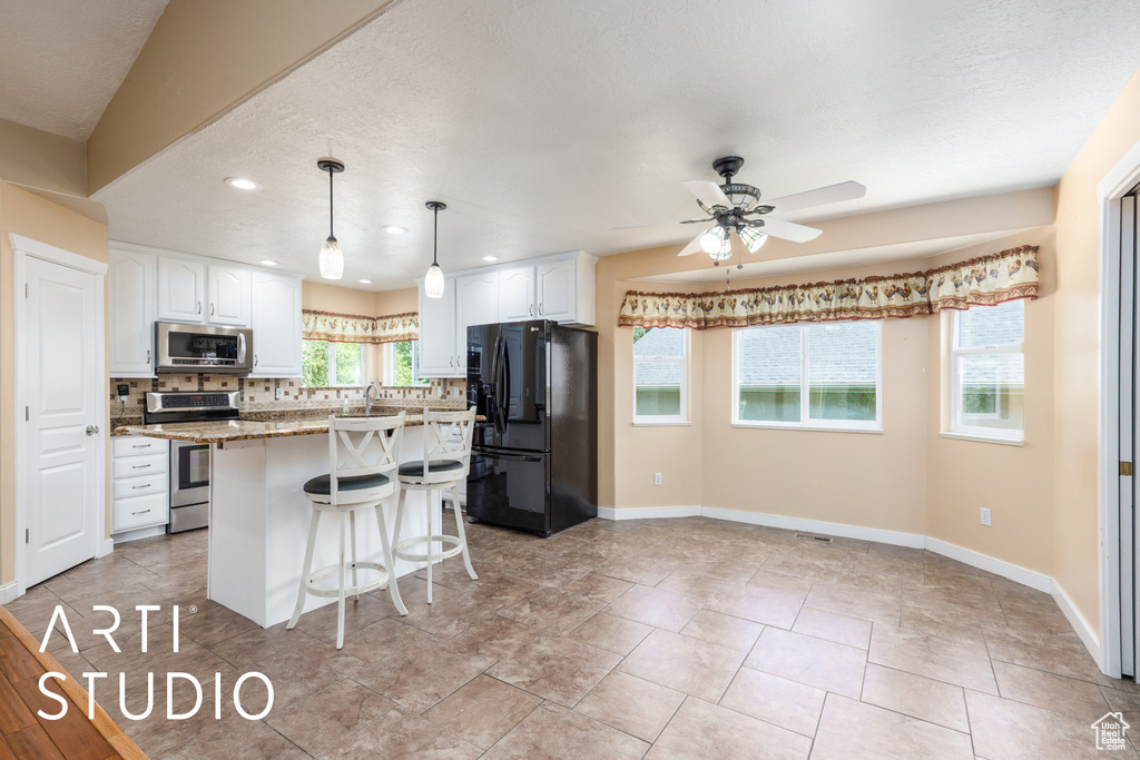 Kitchen featuring appliances with stainless steel finishes, a breakfast bar, decorative backsplash, white cabinetry, and recessed lighting