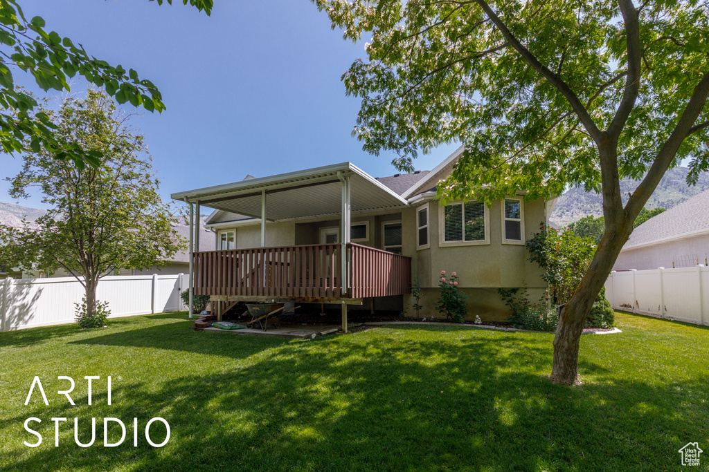View of front of home with a fenced backyard, a deck, and stucco siding
