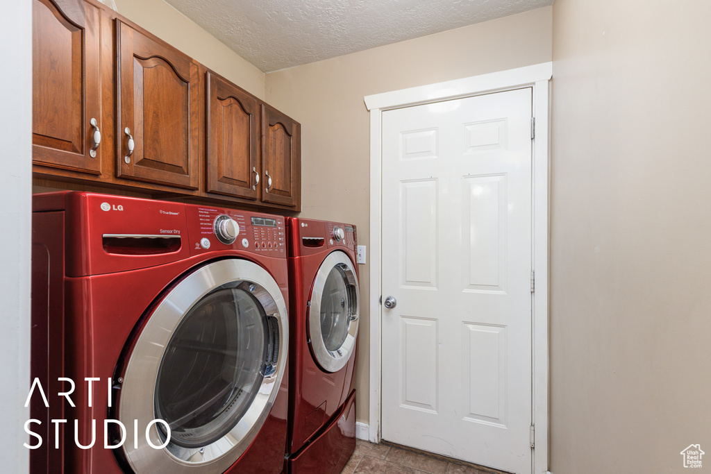 Washroom with washing machine and clothes dryer, cabinet space, and a textured ceiling