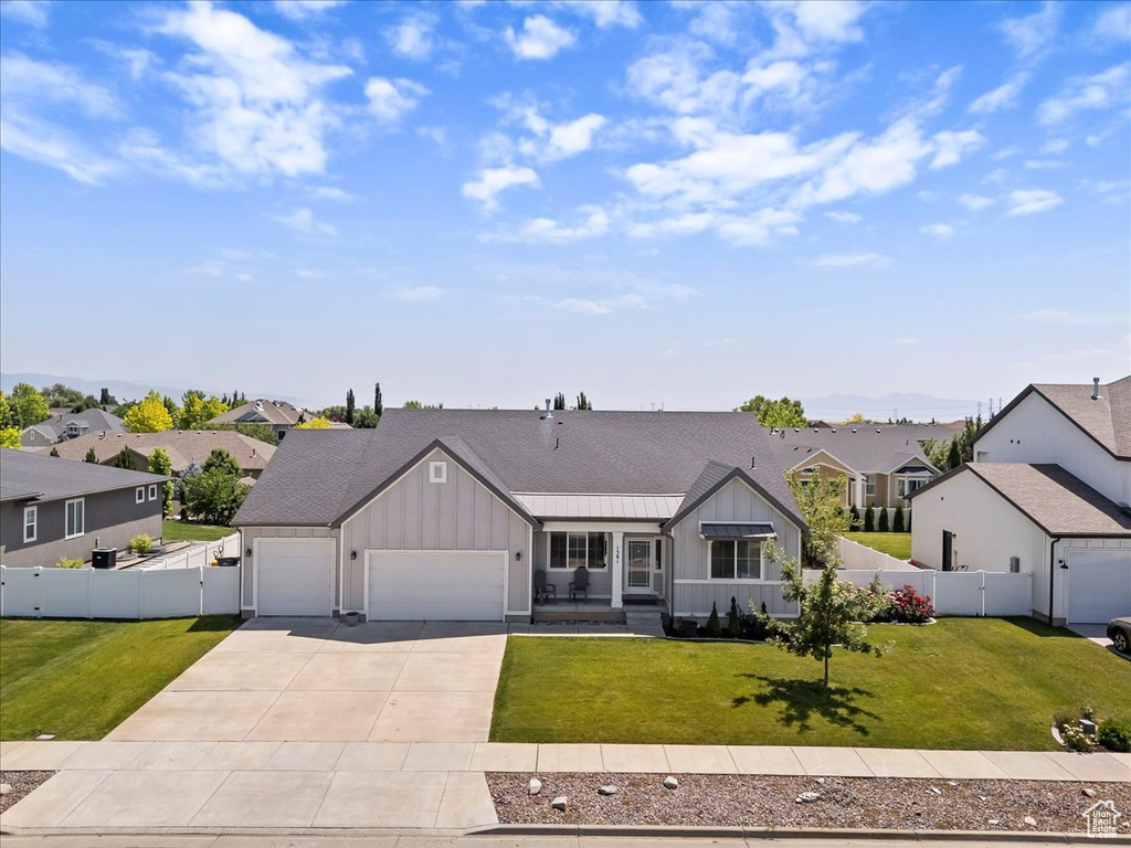 Ranch-style home featuring board and batten siding, a garage, a residential view, driveway, and a gate