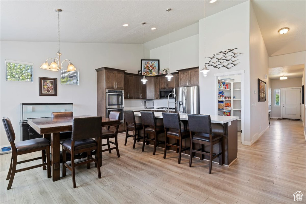 Dining room with high vaulted ceiling, a chandelier, light wood-style floors, healthy amount of natural light, and recessed lighting