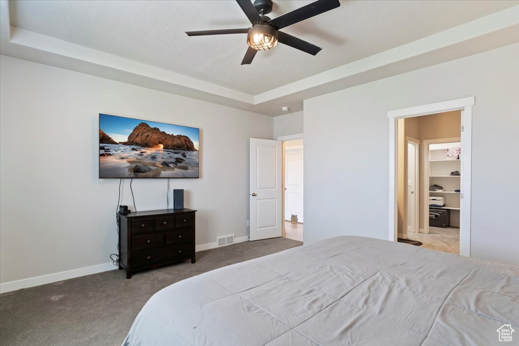 Bedroom with carpet flooring, a tray ceiling, and a ceiling fan