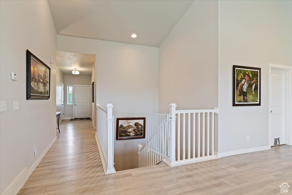 Corridor with an upstairs landing, light wood-type flooring, and recessed lighting