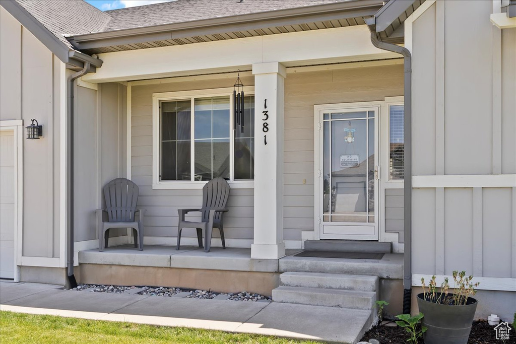Property entrance with a porch and roof with shingles