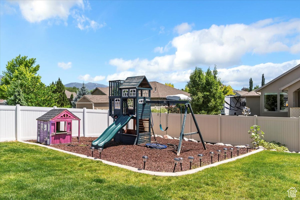 View of jungle gym with a fenced backyard and a mountain view
