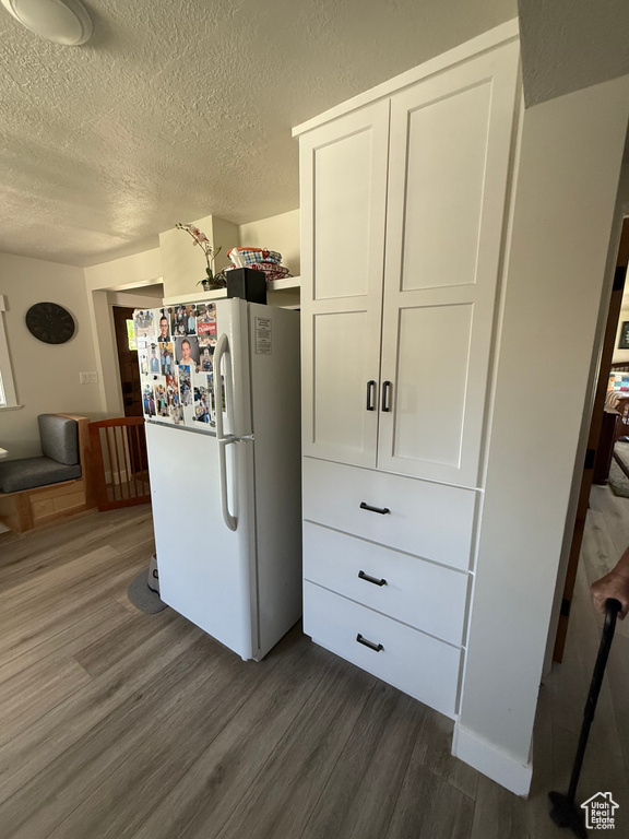Kitchen featuring freestanding refrigerator, dark wood-type flooring, and a textured ceiling