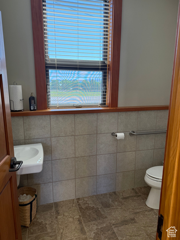 Half bathroom with tile walls and a wainscoted wall