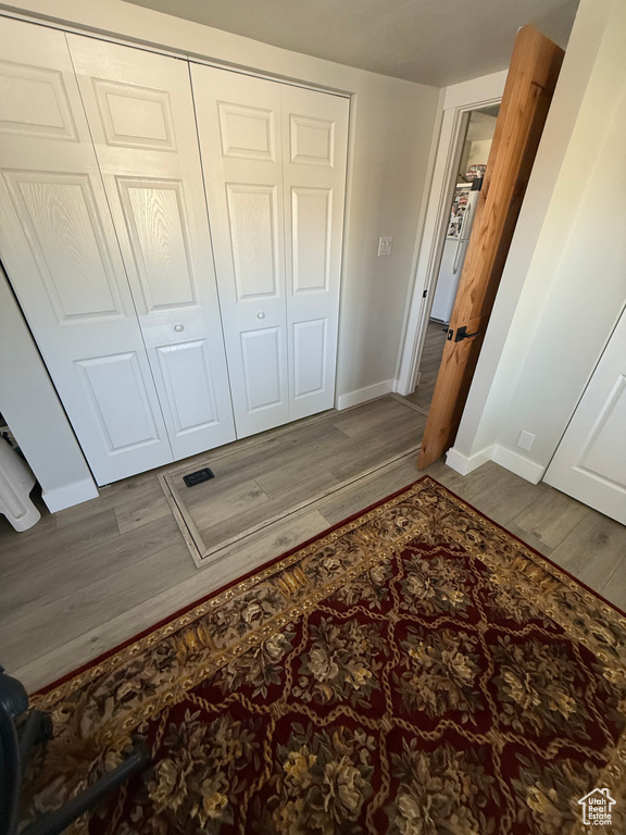 Unfurnished bedroom with wood finished floors, a closet, and freestanding refrigerator