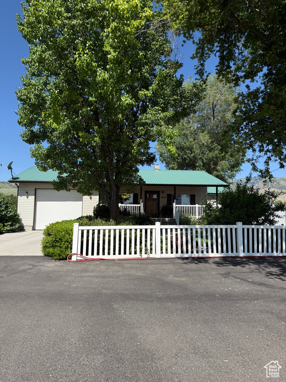 View of front of property featuring a fenced front yard, a metal roof, driveway, and an attached garage