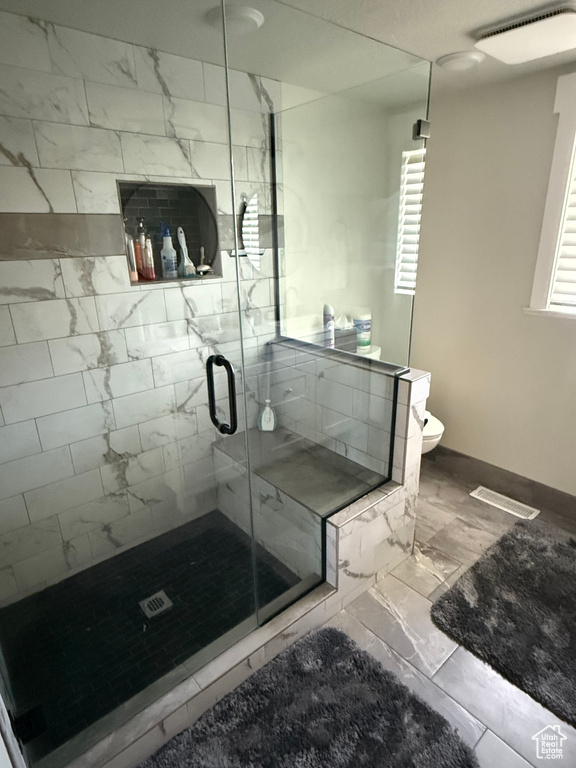 Full bath featuring marble finish flooring and a shower stall