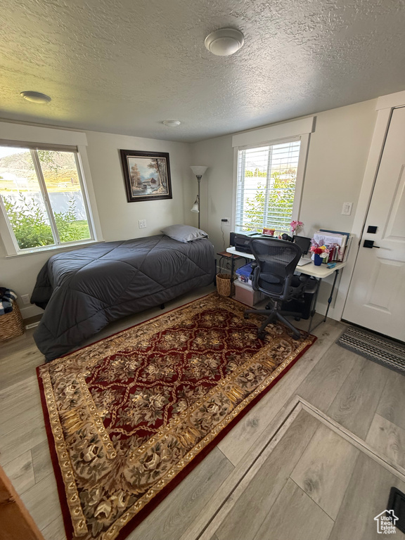 Bedroom with a textured ceiling and wood finished floors