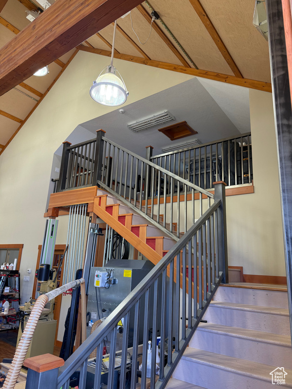 Staircase featuring high vaulted ceiling and beam ceiling