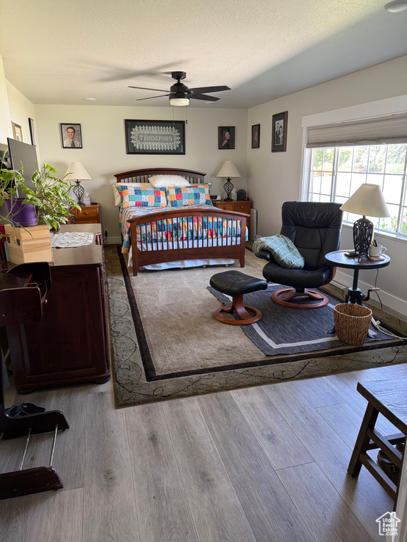 Bedroom with wood finished floors, a textured ceiling, and ceiling fan