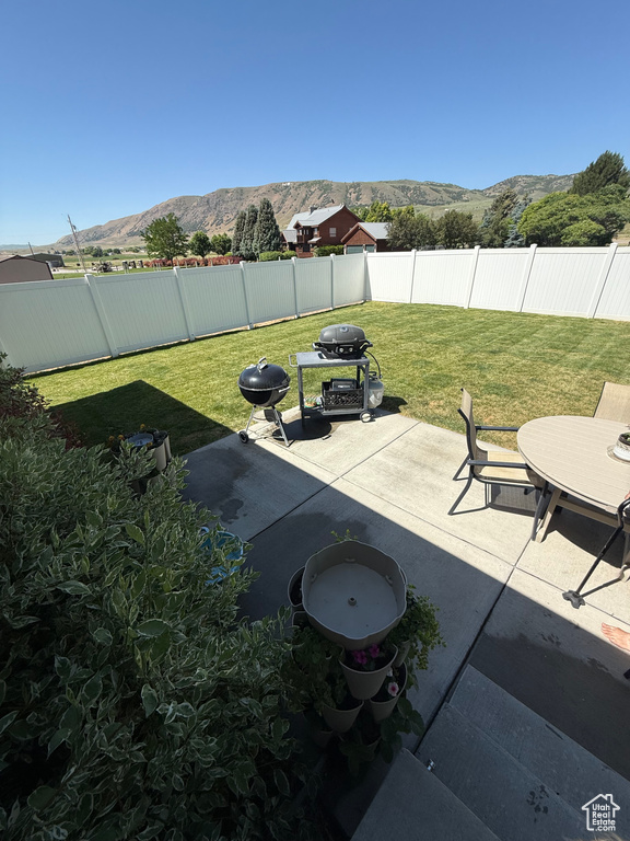 Fenced backyard featuring a mountain view, a patio, and grilling area
