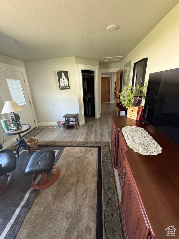 Living room featuring wood finished floors, a textured ceiling, and attic access