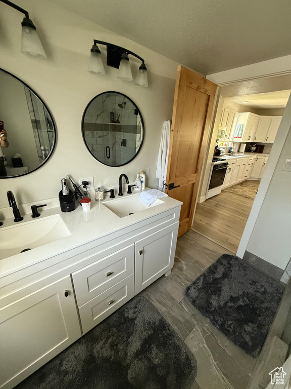 Full bath featuring double vanity, a tile shower, and marble look tile flooring