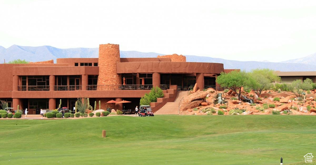 Back of house featuring a mountain view, a yard, and view of golf course