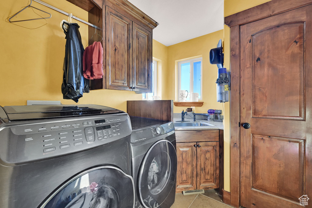 Laundry room featuring cabinets, washing machine and dryer, light tile patterned flooring, and sink