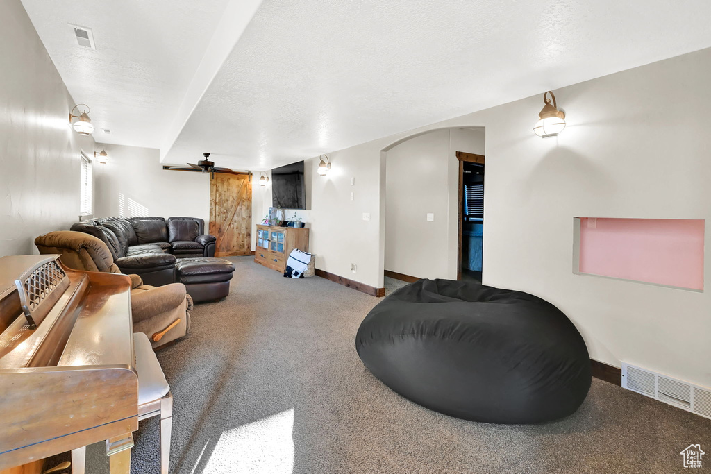 Living room with a barn door, carpet floors, and ceiling fan