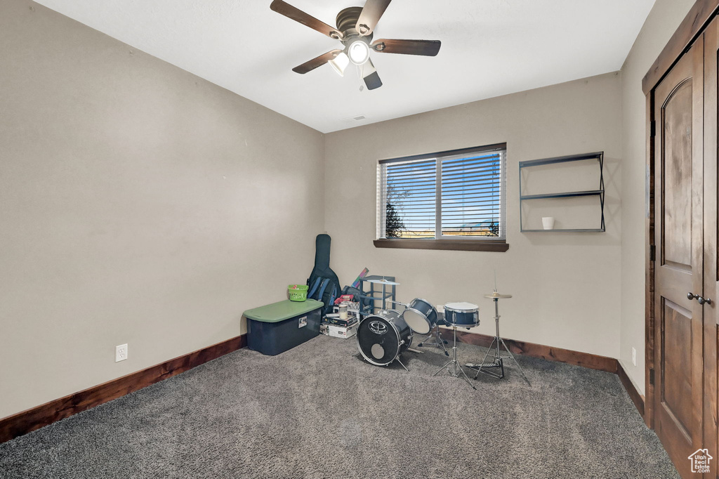 Exercise area with dark colored carpet and ceiling fan