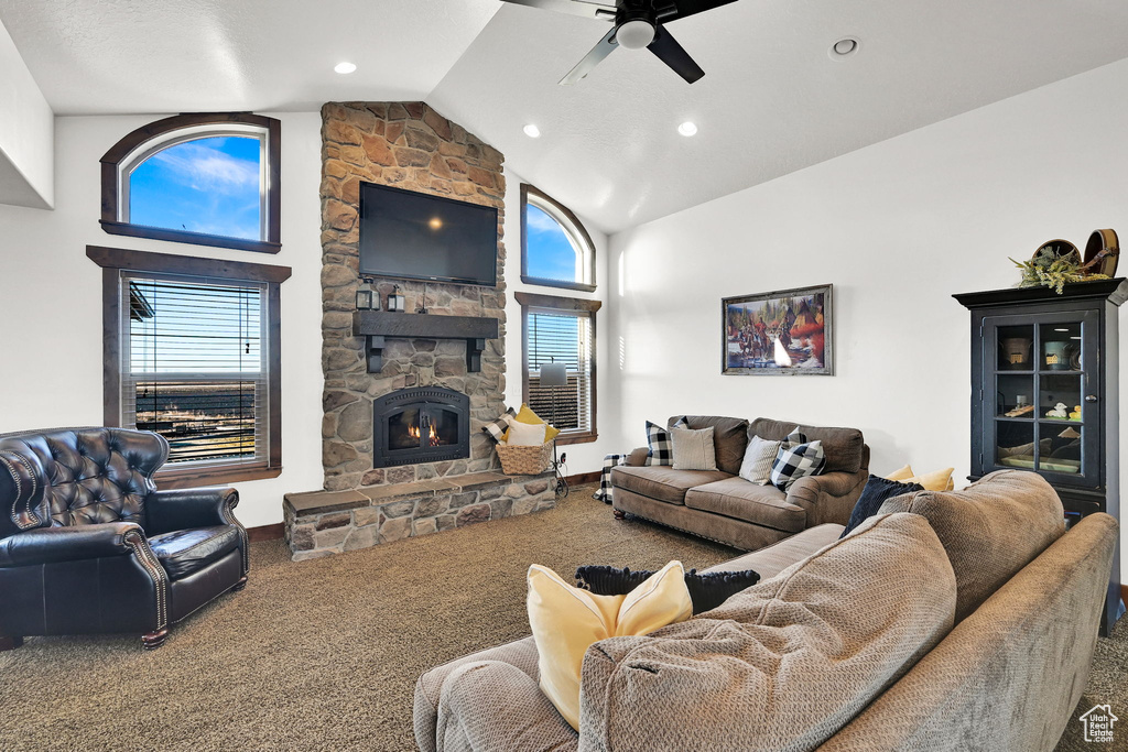 Living room featuring ceiling fan, carpet floors, a fireplace, and high vaulted ceiling