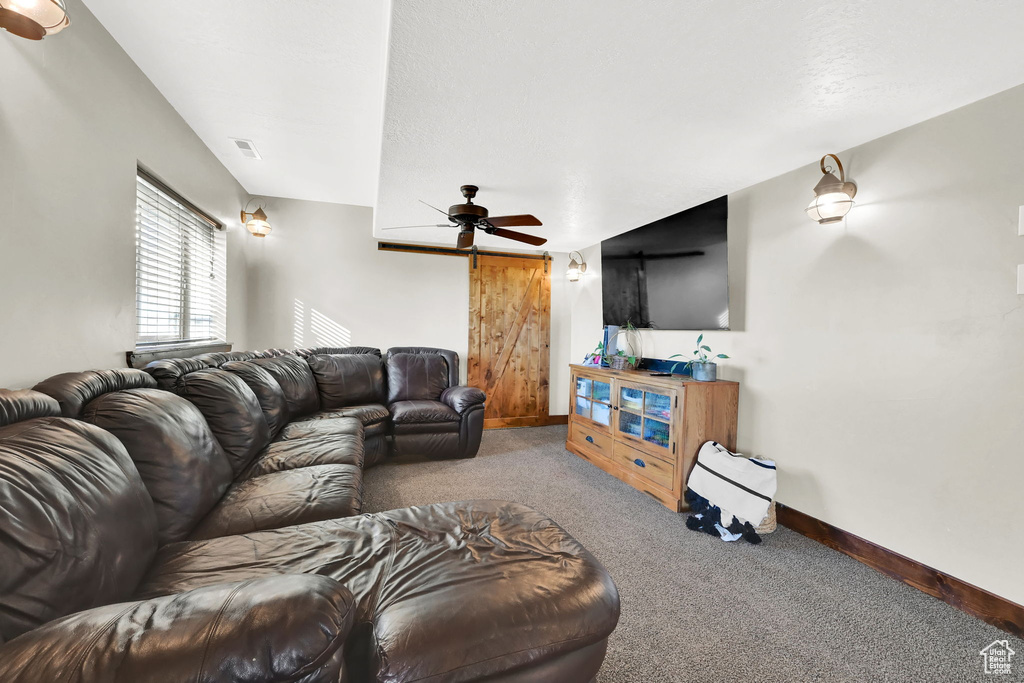 Living room with carpet flooring, ceiling fan, and a barn door