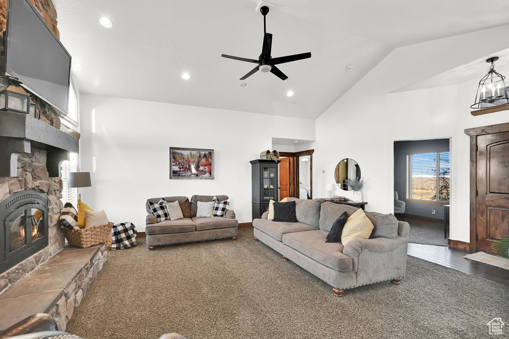 Living room with a stone fireplace, ceiling fan, and high vaulted ceiling