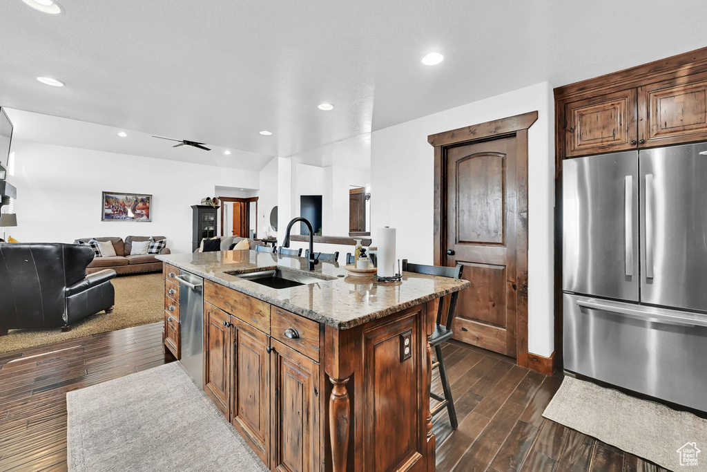 Kitchen with a kitchen breakfast bar, sink, ceiling fan, an island with sink, and stainless steel appliances