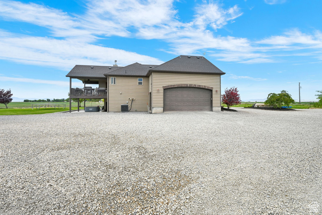 View of side of property featuring a garage and gravel driveway