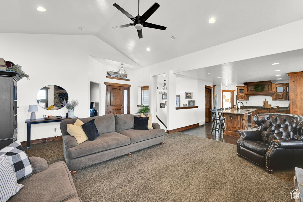 Living room featuring dark hardwood / wood-style floors, high vaulted ceiling, ceiling fan, and sink