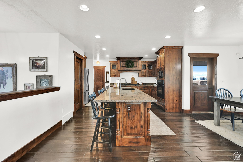 Kitchen featuring sink, stainless steel appliances, dark hardwood / wood-style floors, a breakfast bar area, and a kitchen island with sink