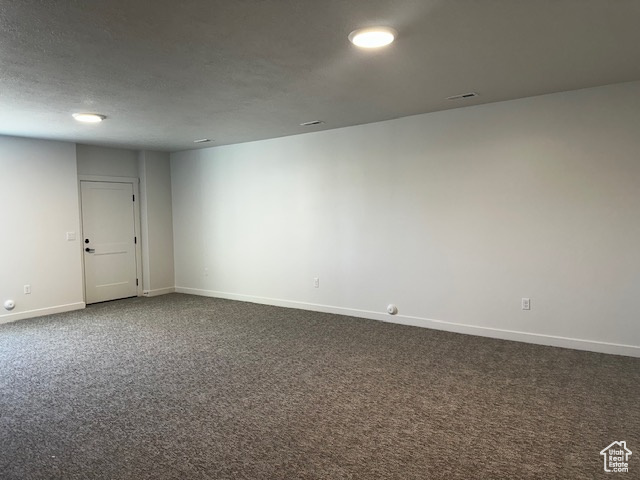 Empty room featuring baseboards and dark carpet