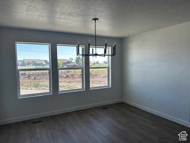 Unfurnished dining area featuring a chandelier, dark wood-type flooring, and a textured ceiling