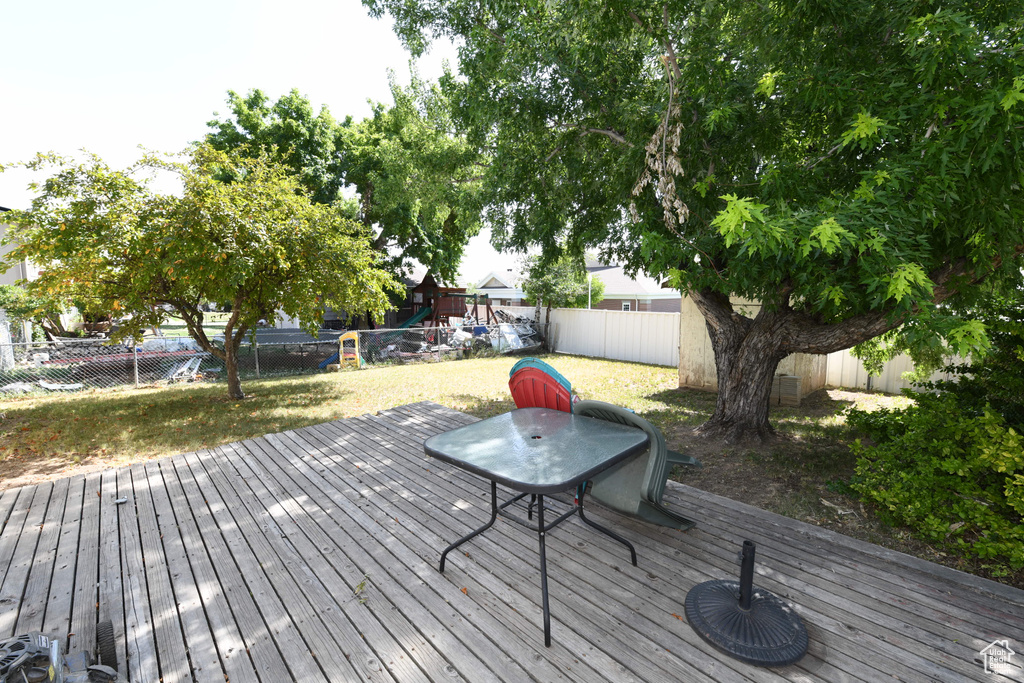 Wooden terrace featuring a playground and a fenced backyard