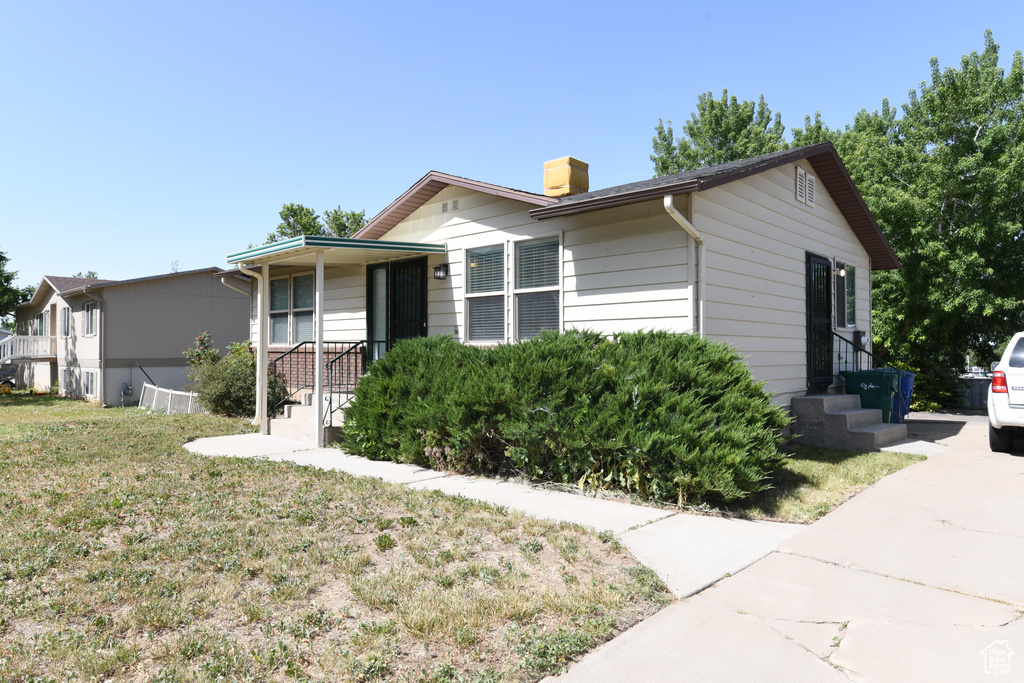 View of front of house with a chimney and a front lawn