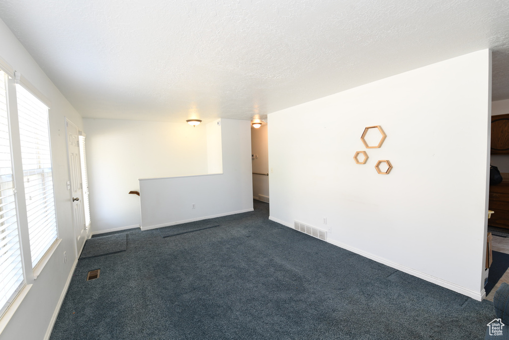 Unfurnished room featuring dark carpet and a textured ceiling