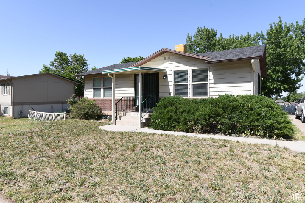 Single story home with a chimney and a front yard