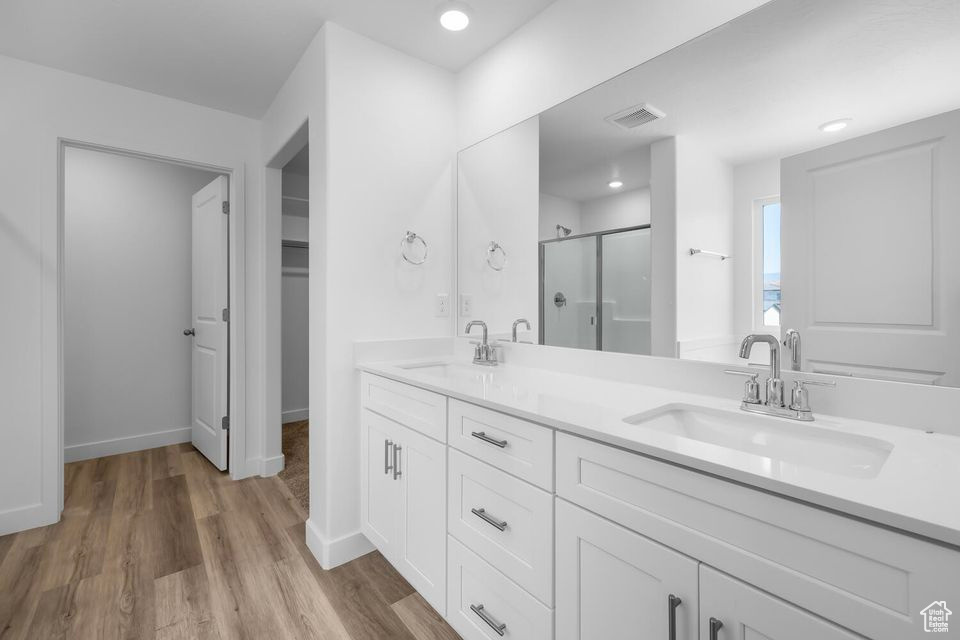 Full bath featuring a shower stall, double vanity, wood finished floors, and recessed lighting