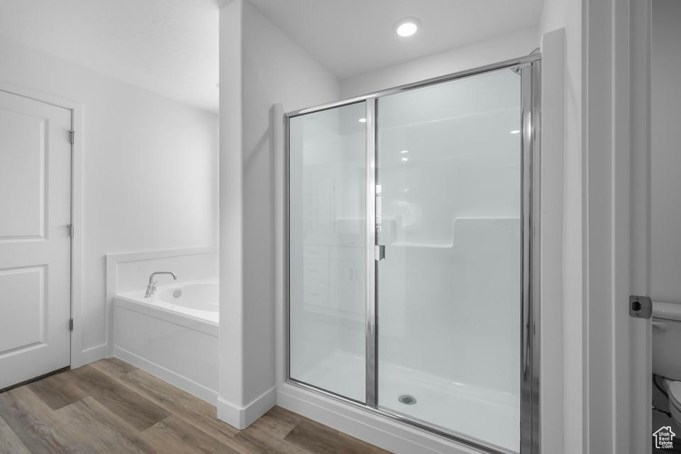 Bathroom featuring wood finished floors, a shower stall, and a garden tub