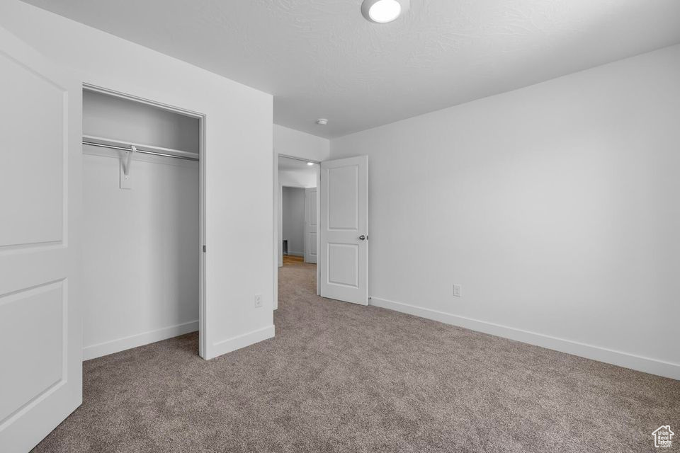 Unfurnished bedroom featuring carpet flooring and a closet