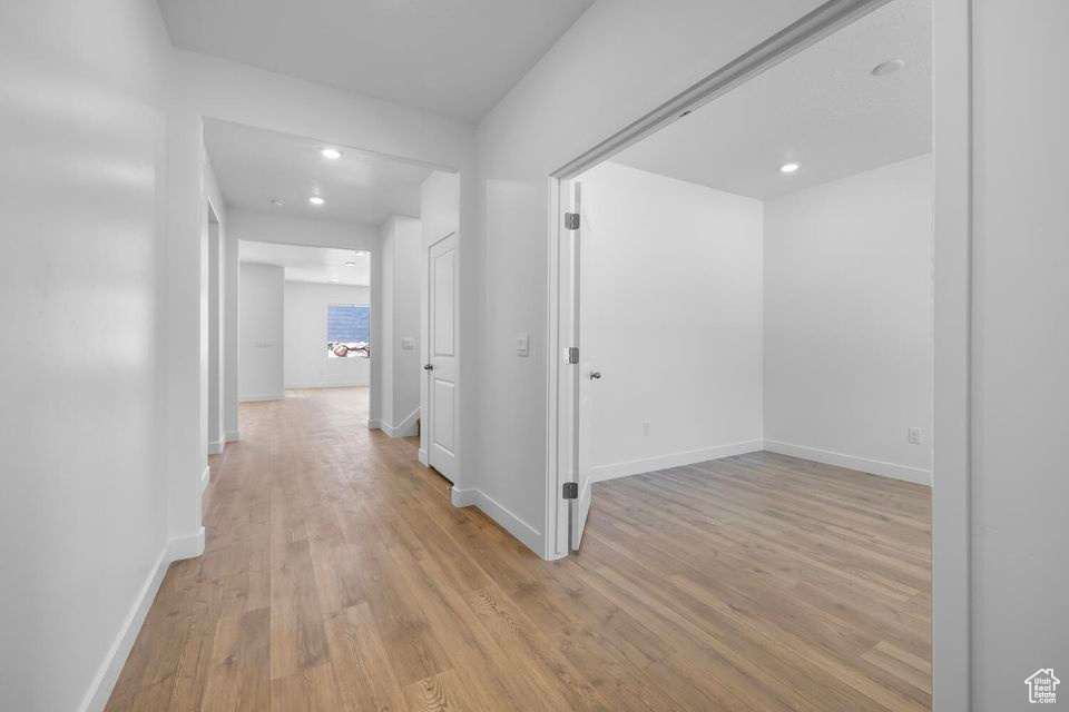 Hallway with light wood-style flooring and recessed lighting